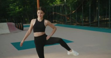 Egzersiz yapan, eğilip dışarı uzanan çekici genç bir kadın. Sağlıklı bayan atlet açık hava yaşam tarzı spor antrenmanından hoşlanır. Yavaş çekim