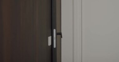 Kapı kolu tutan bir kadının yakın plan görüntüsü, ahşap elementlerle modern bir iç mekan görüntüsü sergiliyor. Ofisteki Kadın Kapı Kolu ya da İç Güvenlik Ayarları