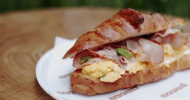 Pastırmalı ve çırpılmış yumurtalı kruvasan sandviçi yakın çekim. Taze vegan kruvasanı. Lezzetli kruvasanla vejetaryen sağlıklı kahvaltı. Popüler kahvaltı.