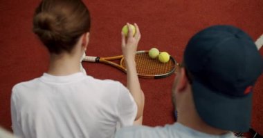 Arkadaşlar dışarıda halı kortunda tenis oynadıktan sonra dinlenip konuşuyorlar. Arkadaşlarla aktif spor oyunu. Tenis oyuncusu iş başında. Tenis maçı. Etkin boş zaman oyunu.
