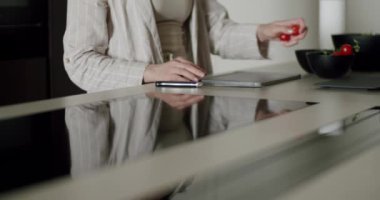 Pürüzsüz, modern bir mutfak ortamında taze domates dilimleyen bir kadın sağlıklı yemek ve yaşam tarzını ön plana çıkarıyor. Modern Mutfak 'ta Kesme Tahtasında Taze Domates Kesen Kadın