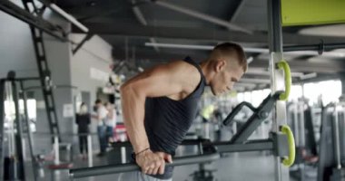 Kendini spora adamış genç bir erkek, yoğun bir spor salonu ortamında gücünü gösteriyor ve odaklanıyor. Modern bir spor salonunda yüzmeye odaklanmış genç adam.