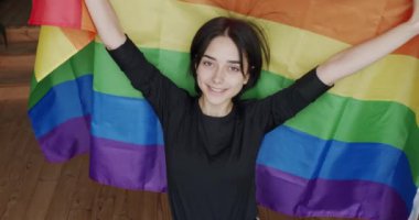 Lgbt kadınları gururlu gökkuşağı bayrağıyla kameraya bakıyorlar. Mutlu bayan ve gülümse. cinsel çeşitlilik, LGBTQI, Gurur Etkinliği, LGBT hakları, yaşam tarzı ve ilişkiler. LGBT kavramı