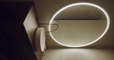 Zarif modern banyo LED ışıklandırmalı ve minimalist bir tekne lavabosu olan büyük dairesel bir ayna içeriyor. Parlak ve çağdaş iç tasarım. Dikey