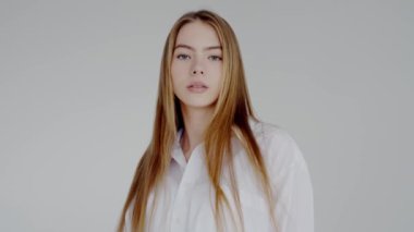 Uzun sarı saçlı ve ince makyajlı sakin genç bir kadının portresi loş bir stüdyoda arkasını kolluyor. Uzun sarı saçlı, Arkaya bakan Serene Genç Kadın