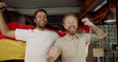 Ulusal Almanya bayrağı taşıyan adamlar spor maçı izliyor. Taraftarlar bir barda arkadaşlarıyla futbol izliyorlar. futbol, hokey, basketbol, spor oyunları.