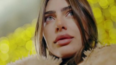 Geceleri şehir merkezinde poz veren güzel bir kadın. Sokaktaki doğal güzellik kraliçesi. Ağır çekim. Akşam şehirde yürürken kameraya bakan kendine güvenen güzel bir kadının portresi.