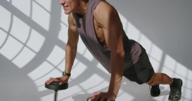 23 yaşında atletik bir adam stüdyoda şınav çekiyor. Dramatik ışıklandırma altında gücünü ve kaslı yapısını gösteriyor. Gölgeli Bir Stüdyoda şınav çeken Atletik Genç Adam
