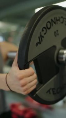 Spor salonundaki ağırlığı kucaklayan, odaklanmayı ve fitness konusundaki kararlılığı vurgulayan bir kişinin yakın çekim görüntüsü. Spor Salonunda Ağırlık Tutarken Yakın Çekim Fitness Üzerine Odaklanma. Dikey