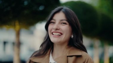 Açık havada gülümseyen neşeli genç bir kadın şehir parkındaki ağaçların bulanık arka planına gülümsüyor. Bir anlık mutluluk, doğa ve şehir yaşam tarzını yakalıyorum. Genç Kadın Dışarda Poz Veriyor