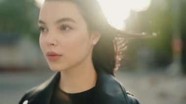 Arka planda hafif ışık ve güneş ışığı parlayan genç bir kadının yakın plan portresi. Görüntü, kadınların yüzlerindeki sakin, sakin ve düşünceli ifadeyi yakalar. Genç Kadın Portresi