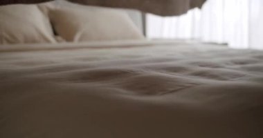 Saf perdelerin arasından doğal güneş ışığıyla yıkanmış, dokulu bir battaniye ve nötr bir ton yatak içeren rahat bir yatağın yakın çekimi sakin ve davetkar bir atmosfer yaratıyor. Yumuşak Battaniyeli Rahat Yatak