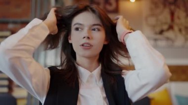 İş elbisesi giymiş genç, düşünceli bir kadın bir kafede oturuyor, muhtemelen mola vermiş ya da tefekkür ediyor. Kentsel Kafe Çevresindeki Kendine Güvenen Genç İş Kadını