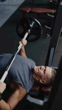 Genç adam spor salonunda göğüs presi egzersizi yapıyor. Egzersize ve güç toplamaya odaklanmış. Fitness, sağlık ve kararlılık. Güçlendirme Eğitimi Dikey Odaklandı