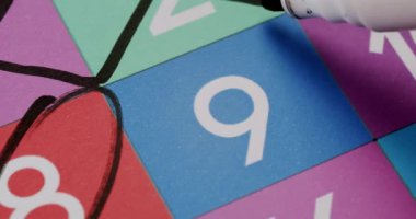 Siyah kalemle işaretlenmiş 9 numaralı renkli tombala kartının yakın plan görüntüsü. Siyah İşaretli 9 Numaralı Bingo Kartının Yakın Çekimi