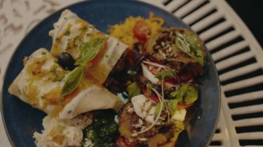 Mavi bir tabakta sunulan taze sebze, bitki ve aromaların karışımından oluşan ağız sulandıran bir Akdeniz yemeği. Yemek severler ve aşçılar için mükemmel..