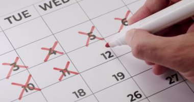 Takvimde günleri kırmızı kalemle işaretleyen, zamanın geçişini, geri sayımı veya önemli tarihleri gösteren bir elin yakın görüntüsü. Takvimdeki Günleri Kırmızı İşaretle Elle Karalamak,