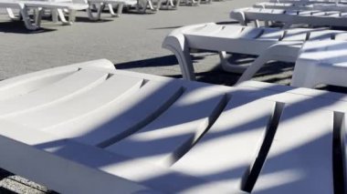 Boş beyaz güneş şezlongları güneşli bir havuz kenarında gölgeler ve dokularla rahatlatıcı bir atmosfer yaratıyor. Güneşli havuz başında Gölgeli Boş Güneş Salonları