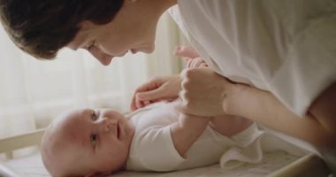 Sevgi dolu anne yeni doğmuş bebeğiyle ilgileniyor. Annelik kavramı. Anne yatağında bebeği için bebek bezi değiştiriyor. Genç anne bebek beyazı değiştiriyor. Evde, yatakta temiz bebek bezi..