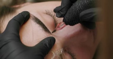 Microblading, permanent makeup tattoo close up. Master makes permanent eyebrow makeup procedure using special needle tattoo machine to woman in beauty salon. Microblading brows tattooing.