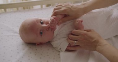 Mutlu anne, küçük bebekle zaman geçirir, küçük ellerini tutar ve nazikçe konuşur. Neşeli anne yeni doğmuş bebeğiyle oynuyor, şefkatle küçük ellerini tutuyor ve komik bir şarkı söylüyor..
