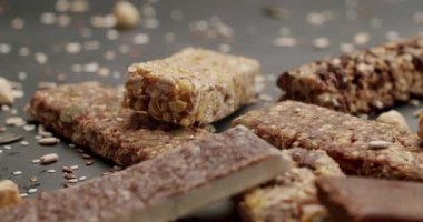Dağınık fındık ve tohumlarla çevrili karanlık bir yüzeyde çeşitli sağlıklı granola çubukları. Besleyici atıştırmalıkları ve sağlıklı beslenmeyi teşvik etmek için mükemmel. Mısır gevreği Enerji Çubuğu