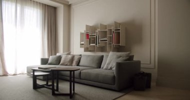 Modern gri bir kanepe, şık kitap rafları ve minimalist dekorun yer aldığı zarif bir oturma odası, rahatlık ve karmaşıklığı vurguluyor. Modern Oturma Odası Koltuğu