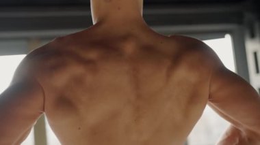 Erkek sporcuların kaslı sırtına odaklanmış bir çekim, spor salonundaki dayanıklılık ve zindeliği vurguluyor. Spor salonunda kaslarını gösteren atletik adam.