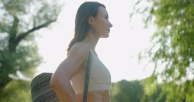 Kadın sporcu. Açık havada bir kadın portresi. Kafasından vur. Sabah koşusundan sonra atlet. Parkta kameraya poz veren güzel bir kadın. Spor sahasında duran beyaz eşofmanlı bir kadın kameraya bakıyor..