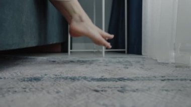 Huzurlu bir yatak odasında yumuşak bir halının üzerinde çıplak ayakla sakin bir yakın plan. Minimalist dekor ve yumuşak ışıklandırma sakinlik ve rahatlama hissini arttırır. Yatak odasındaki Çıplak Ayaklar 'ın Kapanışı