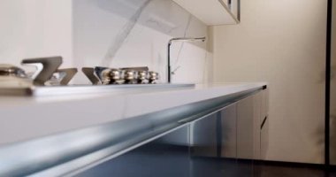 Yemek odasında zarif ve rahat bir ev var. Modern lavabosu olan yerli mutfak. Minimalist yemek masası olan modern mutfak odası. Modern Minimalist Evi. Modern gri ve beyaz mutfak mobilyaları.