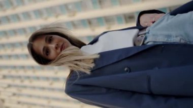 Şehir ortamında kendine güvenen, şık günlük kıyafetlerle süslenmiş şehir mimarisi ile süslenmiş ve kule gibi bir zemin oluşturan genç bir kadının portresi. Günlük kıyafetli genç kadın ayakta duruyor.