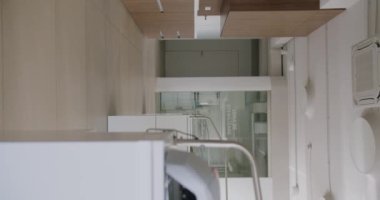 Zarif ve zarif modern ev tasarımı. Minimalist tasarım unsurları ve ahşap ve beyaz ahşap renkler içeren detaylı bir mutfak alanı. Dikey video.