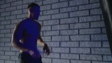 Kas yığını bir spor salonunda kum torbasıyla antrenman yapan, duvar arkası tuğlalı, formda ve azimli bir adam. Kum Torbasıyla Spor Salonunda Tuğla Duvarlı Adam Eğitimi