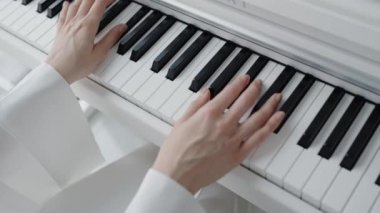 Piyano tuşları çalan ellerin yakın plan görüntüsü, parlak ve zarif bir ortamda müzikal yetenek ve beceri sergiliyor. Müzik, yaratıcılık ve sanat temaları için mükemmel. Eller Kapalı Piyano Anahtarları Çalıyor