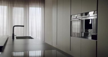 Gösterişli, modern mutfak vitrinli minimalist tasarım, dahili cihazlar, şık bir musluk ve yumuşak perdelerin arasından ince bir ışık filtresi. Modern Mutfak İçi