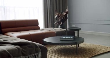 Gri ve kahverengi mobilyalı modern Minimalist oturma odası. Köşedeki kanepe ve yuvarlak masalı lüks Modern Ev İçi. Minimalist iç mekan. Modern Mobilya Tasarımı. Zarif Oda