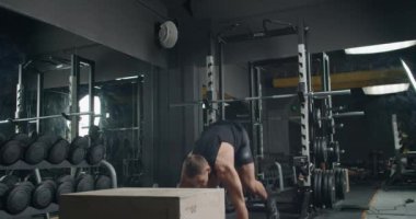 Odaklanmış bir erkek atlet, iyi donanımlı, çağdaş spor salonu ortamında patlayıcı bir atlayış gerçekleştiriyor. Güç ve çeviklik sergiliyor. Modern Spor Salonunda Yüksek Yoğunluklu Kutu Atlayışı Yapan Genç Sporcu