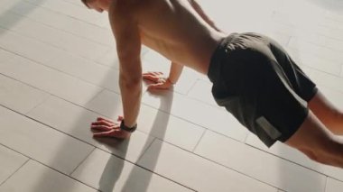 Formda bir genç, kendini adamışlığını ve fiziksel gücünü sergileyerek güneşli bir spor salonunda şınav çeker. Parlak Aydınlık Spor Salonu 'nda şınav çeken Genç Adam