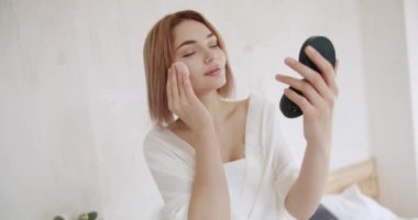 Vücut bakımı. Cilt bakımı ve temizlik prosedürü. Losyonla cilt nemlendirici. Dermatoloji, gözler kapalı ve cilt temizliği ve sağlıklı cilt için makyaj malzemelerini çıkarmak için yüz yastıklı kadın modeli
