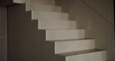 Yumuşak ışıklandırma, minimalizm ve mimariyi vurgulayarak modern, temiz kaplamalı bir merdiven üzerine yumuşak gölgeler bırakır. Yumuşak Işıkta Modern Minimalist İç Merdiven