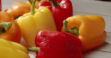 Tahta bir masa üstünde taze, canlı sarı, kırmızı ve turuncu dolmalık biberler. Yemek pişirmek, sağlıklı yemek yemek ve vejetaryen ya da vejetaryen yemek kavramları için mükemmel. Canlı Taze Sebzeler