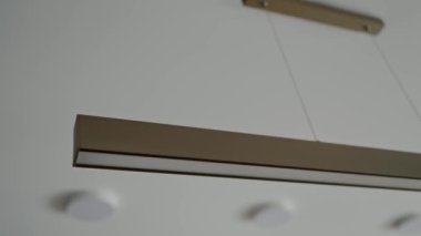 Bir evdeki modern, minimalist bir aydınlatma armatürünün yakın plan görüntüsü. Gösterişli bir tasarıma sahip ve çağdaş iç dekorasyon tarzlarının temsilcisidir. Parlak Işıklı Modern Minimalist Ev İçi