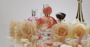 Bu resim zarif parfüm şişelerini zarif güller ve taç yaprakları arasında sergiliyor. Lüks ve tazelik hissi uyandırıyor. Etrafı güzel gül ve yapraklarla çevrili zarif parfüm şişeleri.
