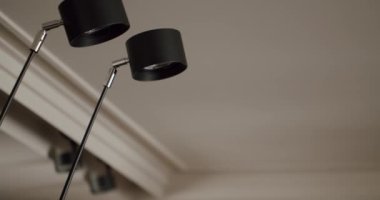 Minimalist bir iç mekanda modern siyah tavan lambalarının yakın çekimi. Şık ve gösterişli aydınlatma armatürleri aydınlatma sağlar ve mekana çağdaş bir zarafet katar. Kara Tavan Lambaları