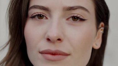 Genç bir kadının samimi yakın çekimi, ela gözlerini, doğal makyajını ve huzurlu ifadesini gösteriyor. Büyüleyici Hazel Gözlü Genç Bir Kadının Yakın Çekim Portresi