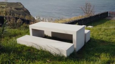 Beton piknik masası ve Portekiz 'de okyanusa bakan çimenli bir uçurumun kenarındaki banklar. Rahatlamak ve doğanın tadını çıkarmak için ideal bir ortam. Somut Okyanus Görünümlü Piknik Masası