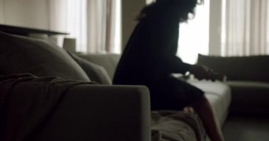Kanepede tek başına, derin düşüncelere dalmış, perdelerden içeri giren bir kadının huzurlu bir görüntüsü. Loş Aydınlatma Odasında Sessizce Oturan Düşünceli Kadın
