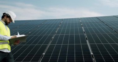 Checking the panels at solar energy installation. Solar cells will be an important renewable energy of the future. The technician in uniform makes notes in the notebook.