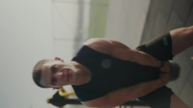 Kollarını esneten kaslı genç bir adamın dinamik görüntüsü, dışarıda spor yapmaya hazırlanıyor, spor ve sağlığa odaklanıyor. Genç Erkek Sporcu Açık hava antrenmanından önce kollarını esnetiyor. Dikey video.